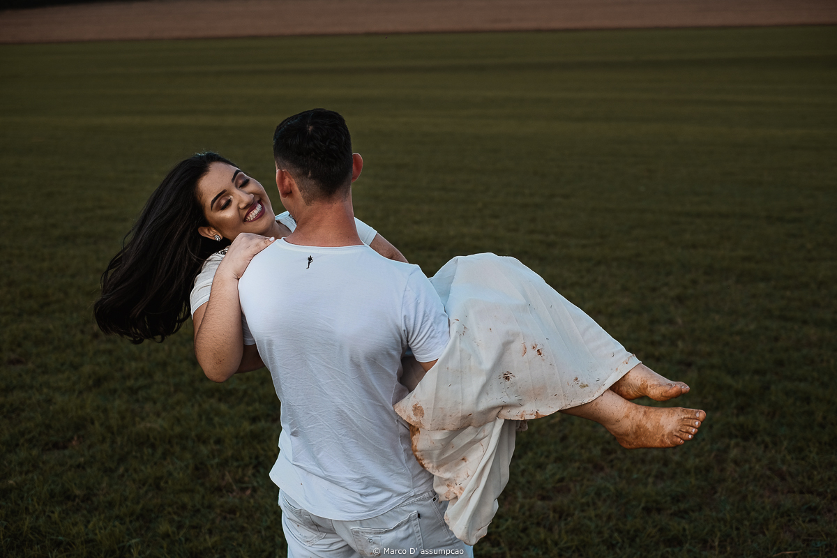 noivo segurando a noiva no colo e girando no gramado