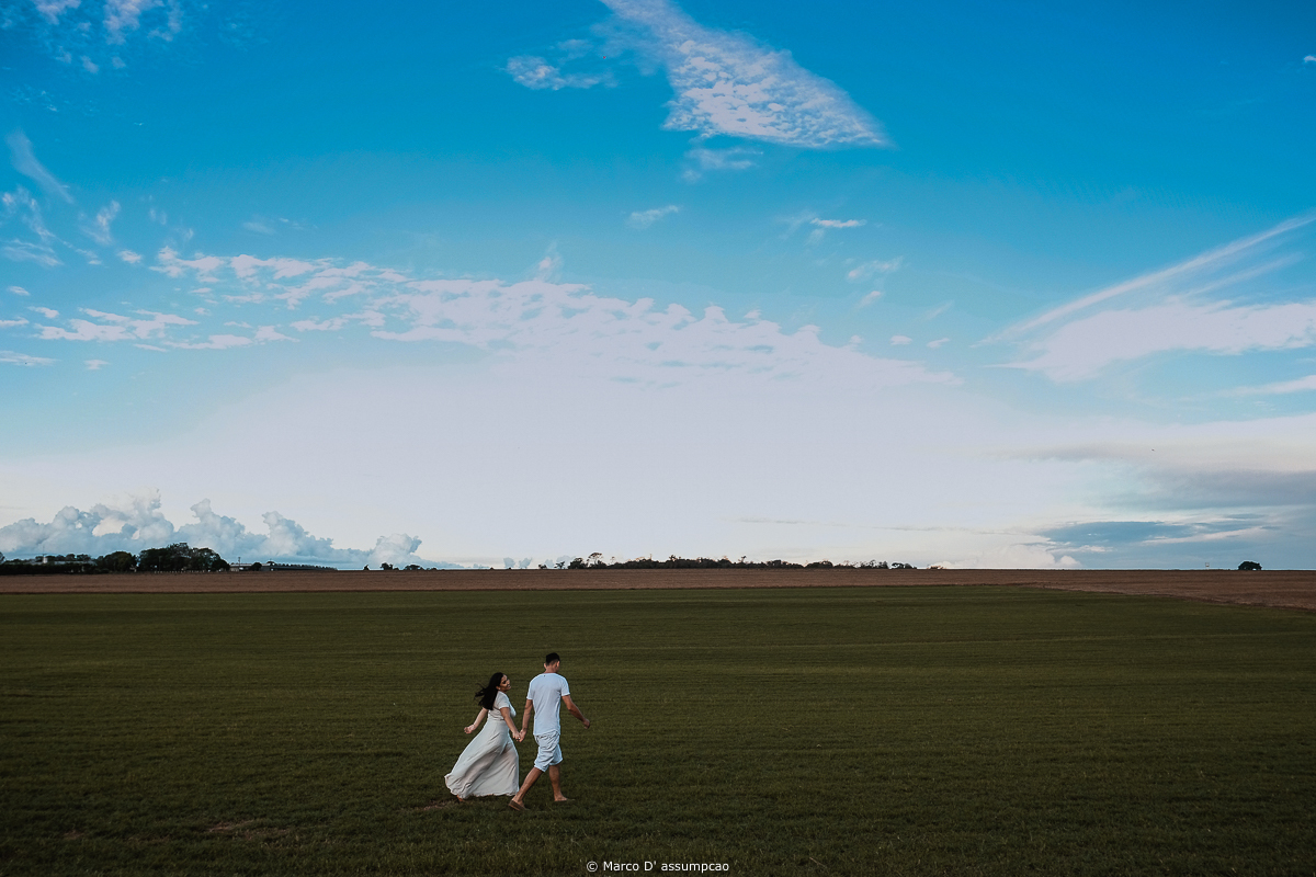 casal caminhando no gramado com o ceu azul