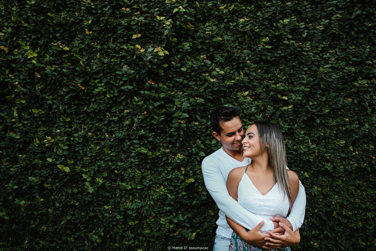 casal se abracandoencostados em uma parede com plantas