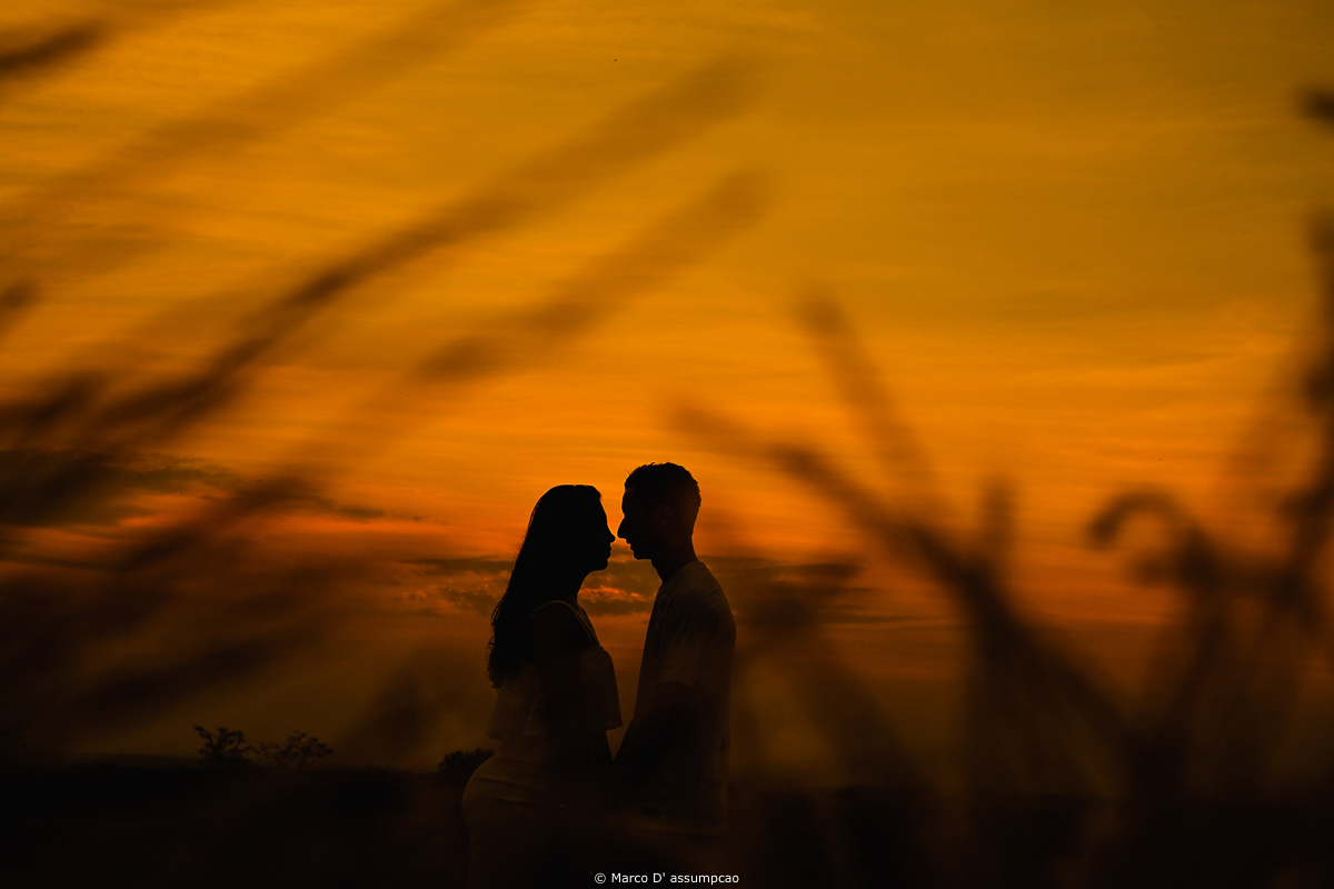 casal encostados em silhueta com por do sol