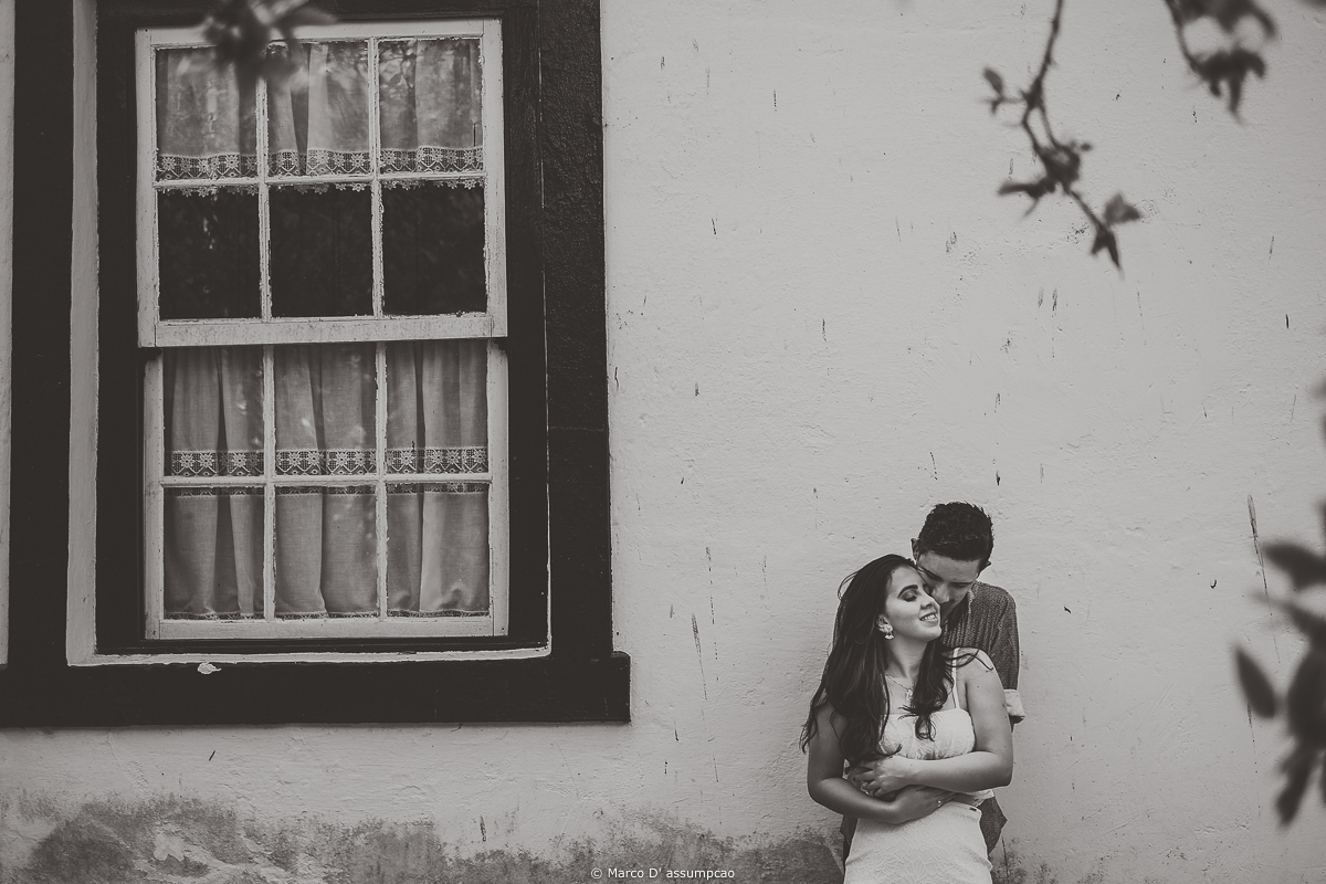 casal abracados ao lado de janela de fazenda