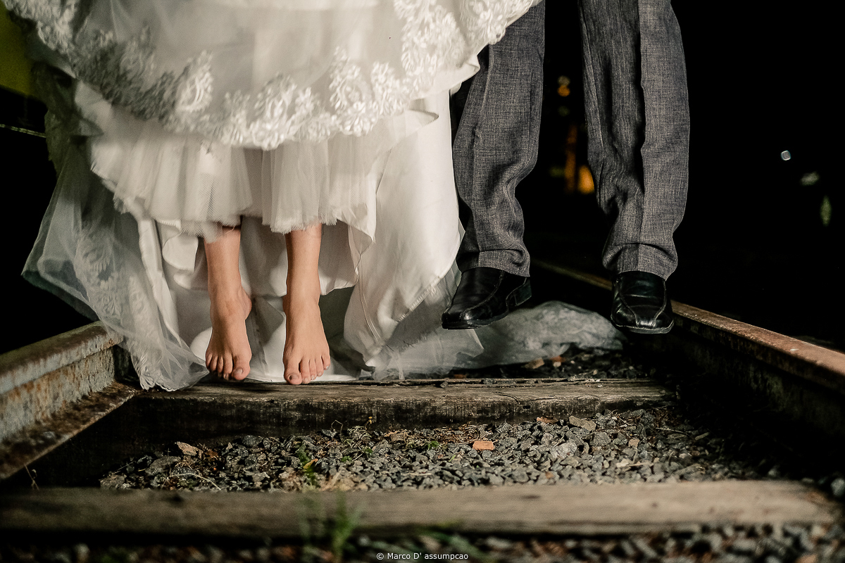 noivos pulando com os pes no trilho de trem