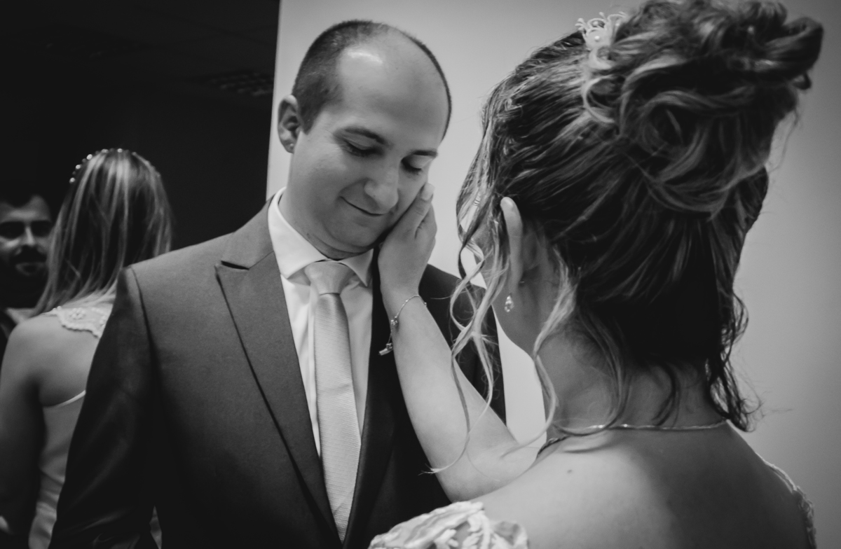 noiva faz carinho no rosto do noivo emocionado