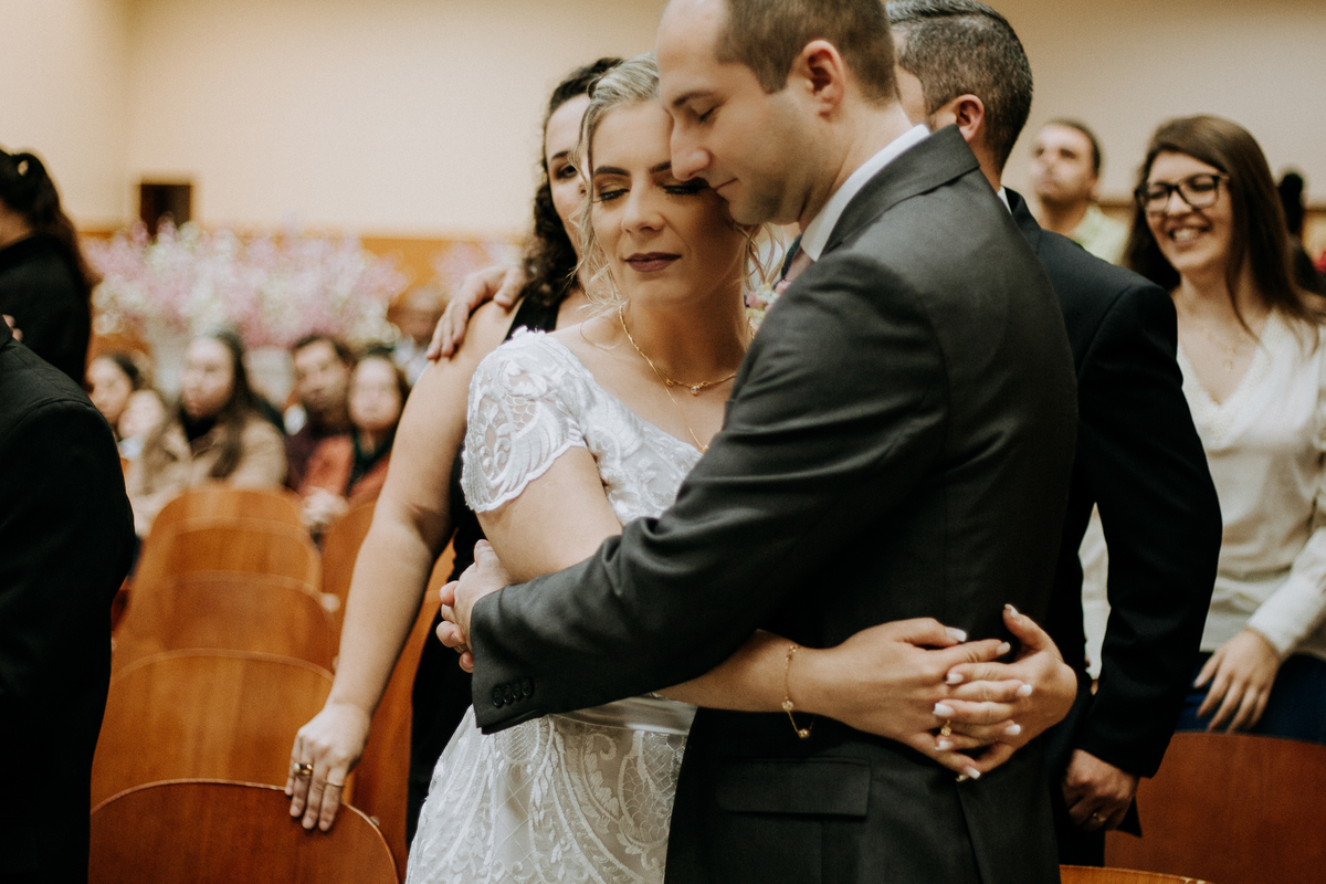 noivo e noiva de olhos fechados, abraçados e orando