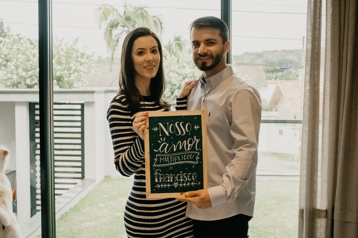 casal segurando plaquinha com nome do bebe