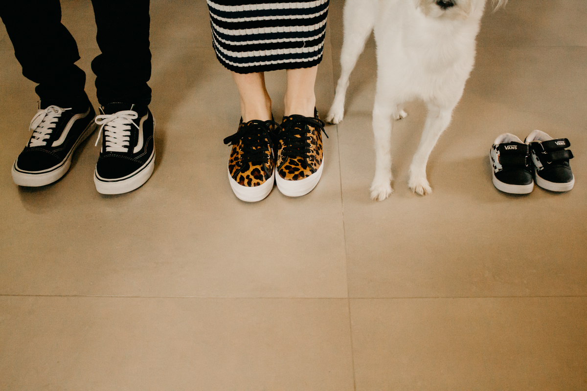 fotografia dos pés dos futuros pais e do tenis do bebe, com as patinhas do cachorro