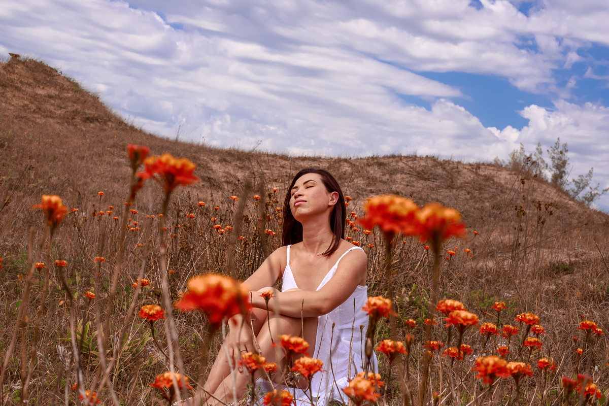 MULHER EM MEIO A FLORES LARANJAS, MULHER NA PRAIA, ENSAIO FEMININO