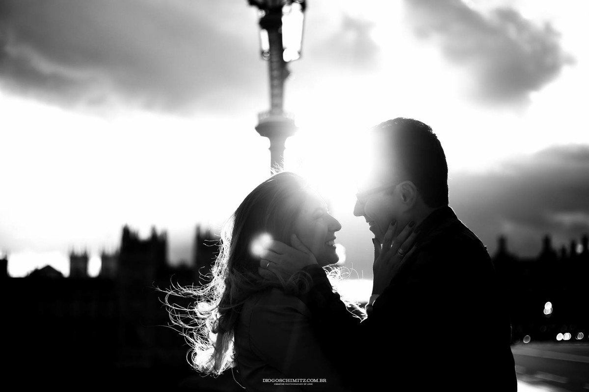 Casal gentilmente segurando o rosto um do outro e sorrindo.