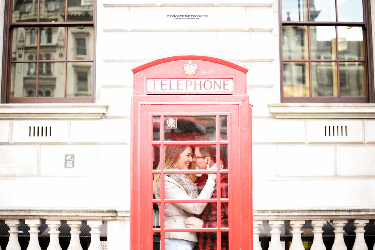 Casal se abraçando dentro de uma cabine telefônica.