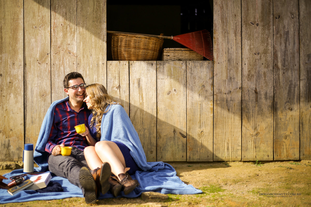 Casal sentado, se abraçando enquanto a mulher é envolta em um covertor azul.
