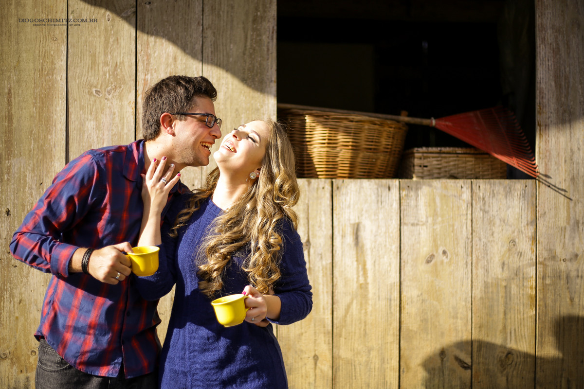 Casal se divertindo enquanto seguram xícaras amarelas.
