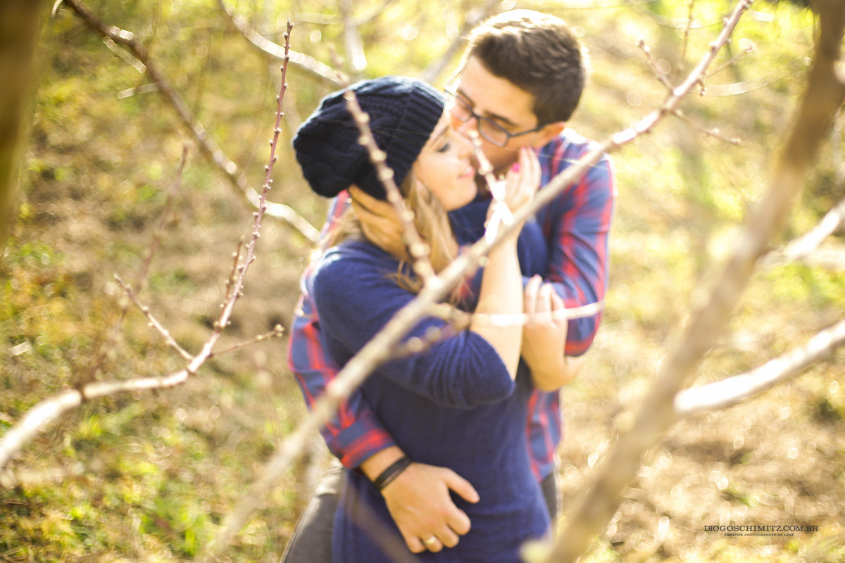 Homem abraçando a mulher pelas costas, e a beijando no rosto.