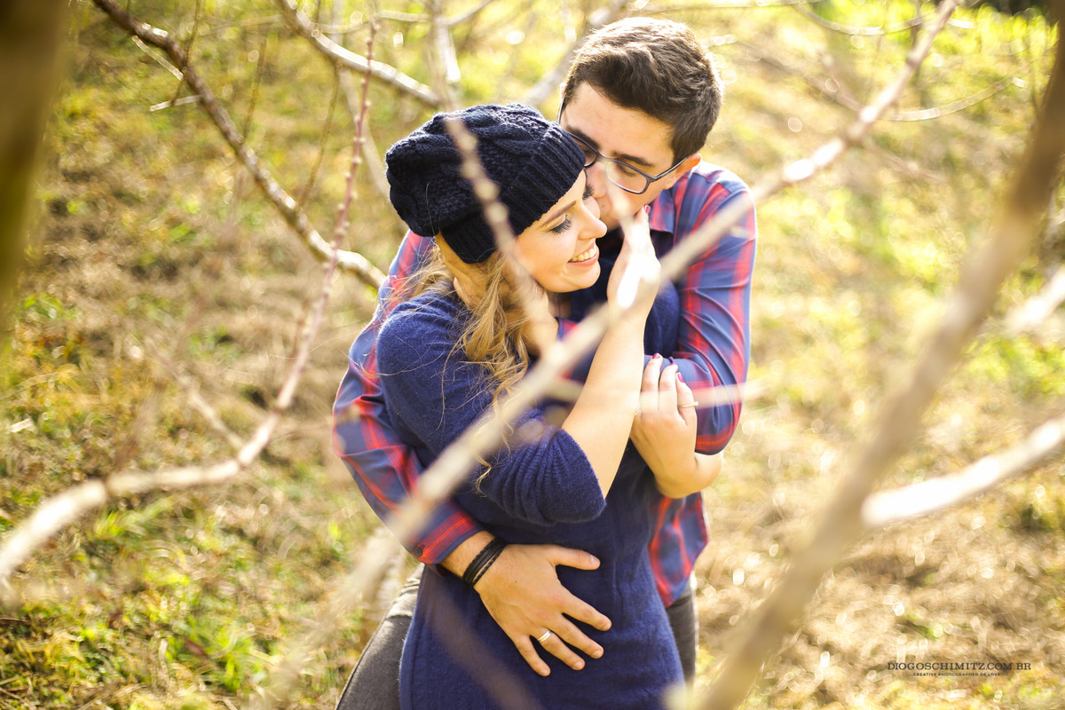 Homem beijando a mulher no rosto enquanto ela sorri.
