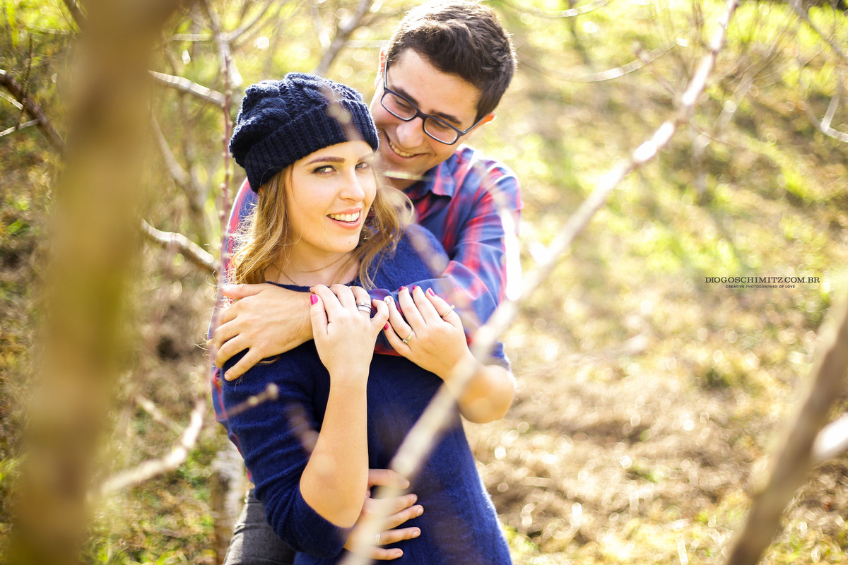 Casal se abraçando, enquanto o homem olha para a mulher, ela olha para a frente.