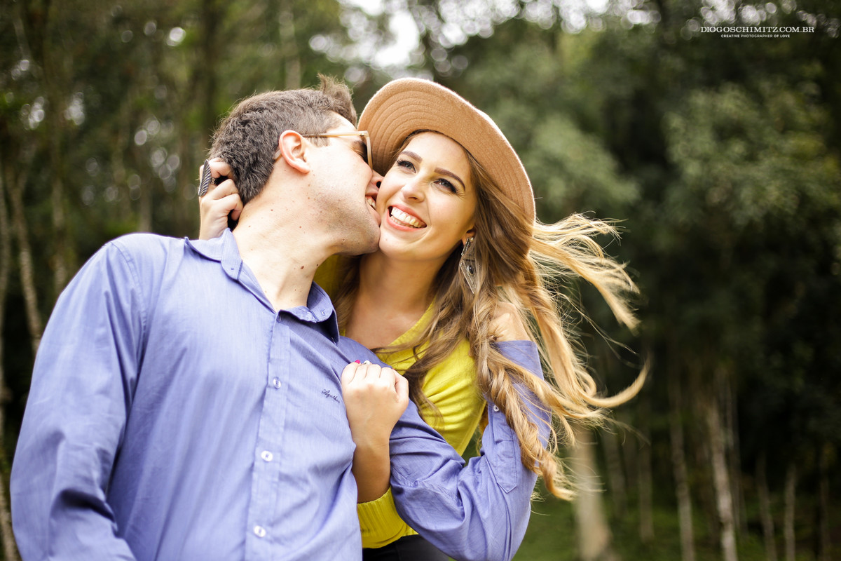 Homem mordendo a bochecha da mulher enquanto ela ri.