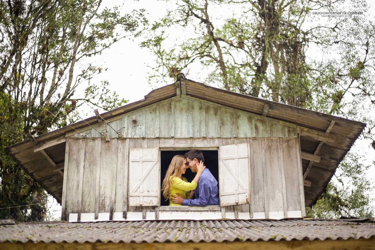 Casal se abraçando em frente a uma janela.