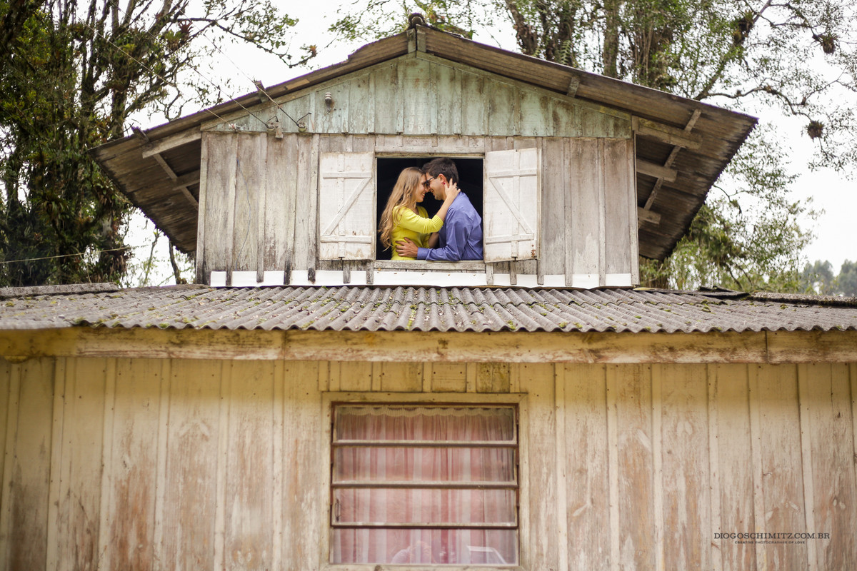 Casal se divertindo e rindo em frente a uma janela.