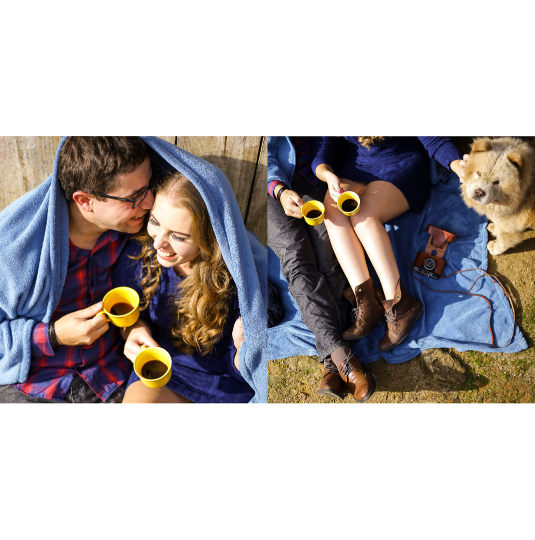 Casal sentado, segurando xícaras amarelas com café preto e rindo.