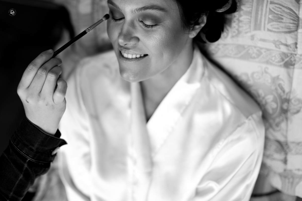 Maquiadora finalizando a maquiagem da noiva.
