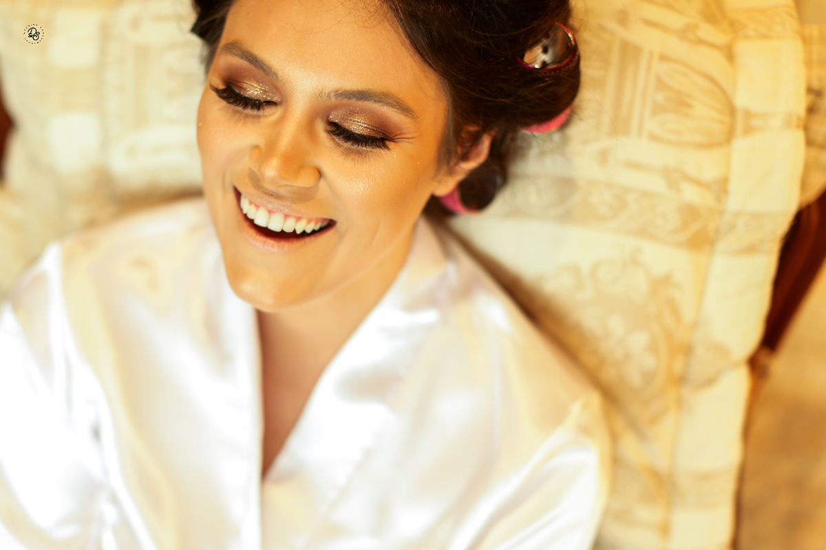 Noiva sorrindo ao ser maquiada.