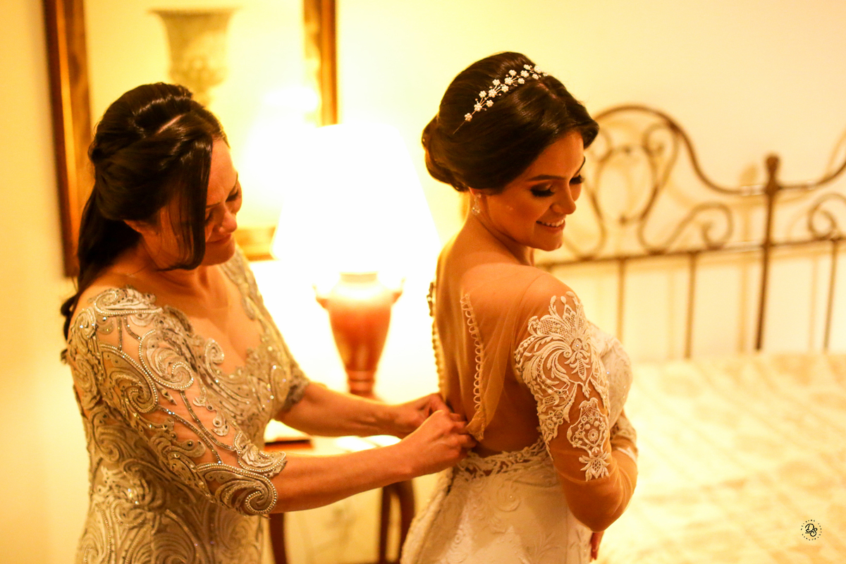 Mãe da noiva ajudando a fechar o vestido.