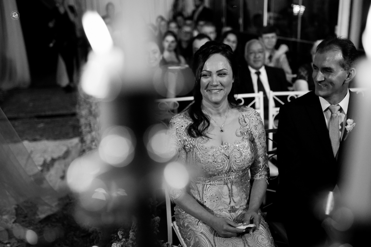 Mãe da noiva sorrindo ao assistir a cerimônia.