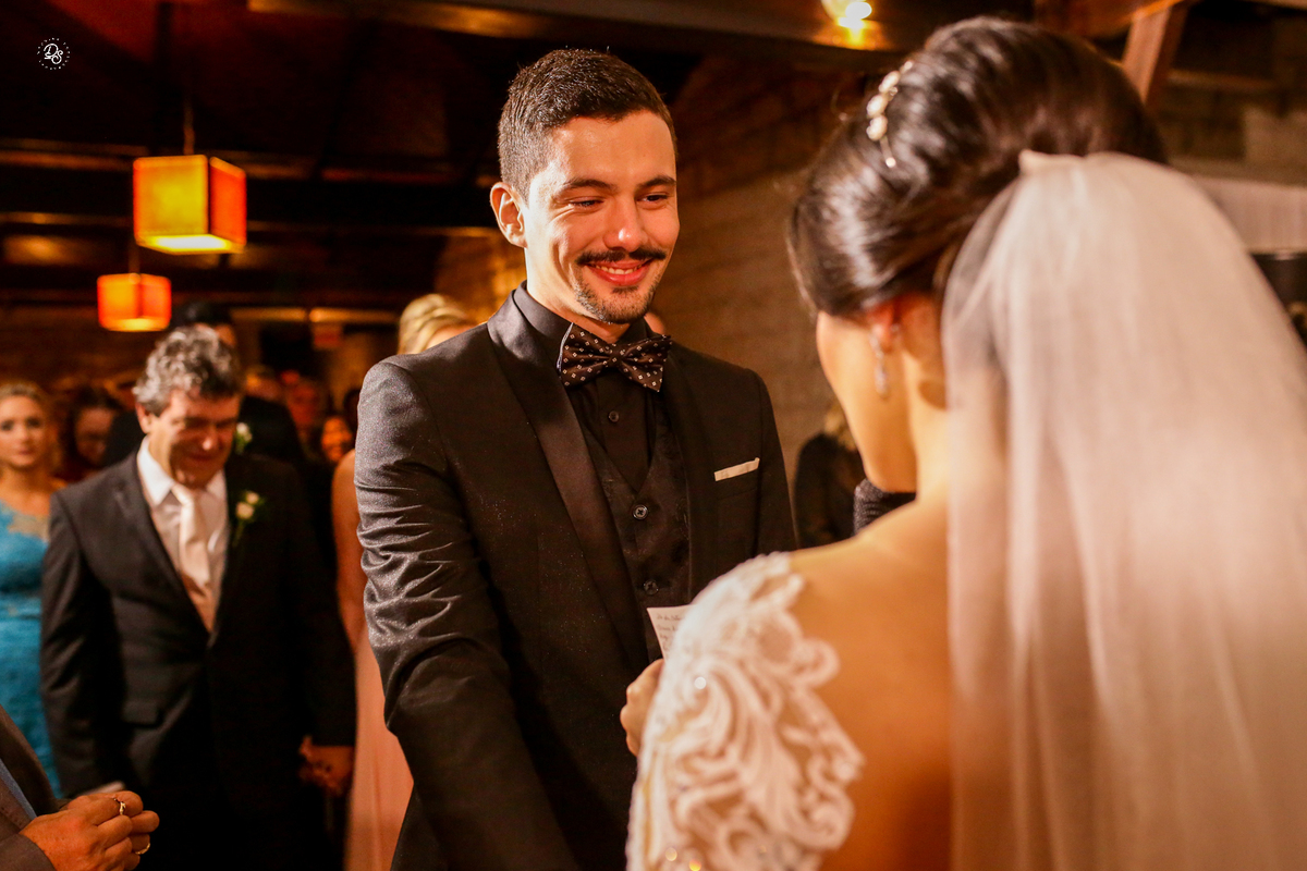Noivo sorrindo para a noiva na hora dos votos. 