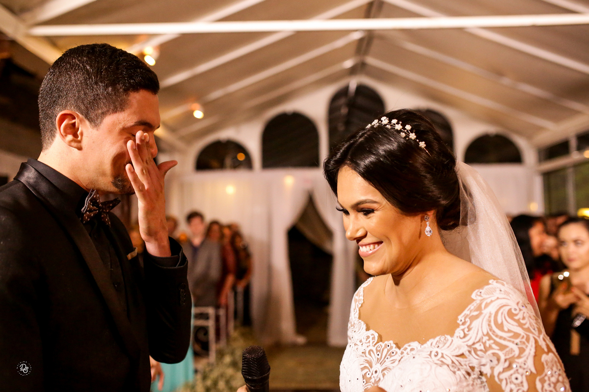 Noivos sorrindo ao trocar votos.