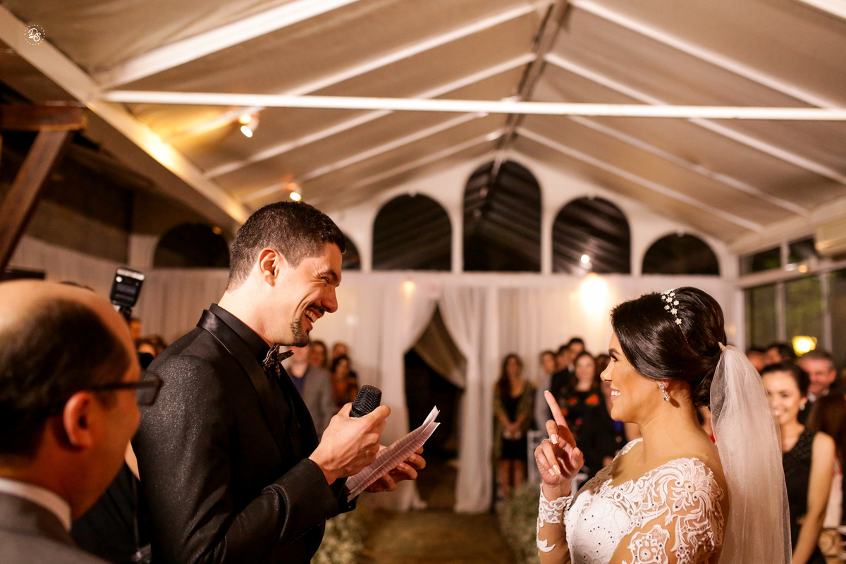 Noiva apontando para o noivo e sorrindo. 