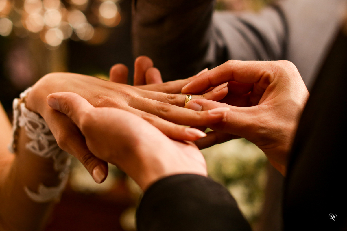 Momento em que noivo coloca a aliança no dedo da noiva.