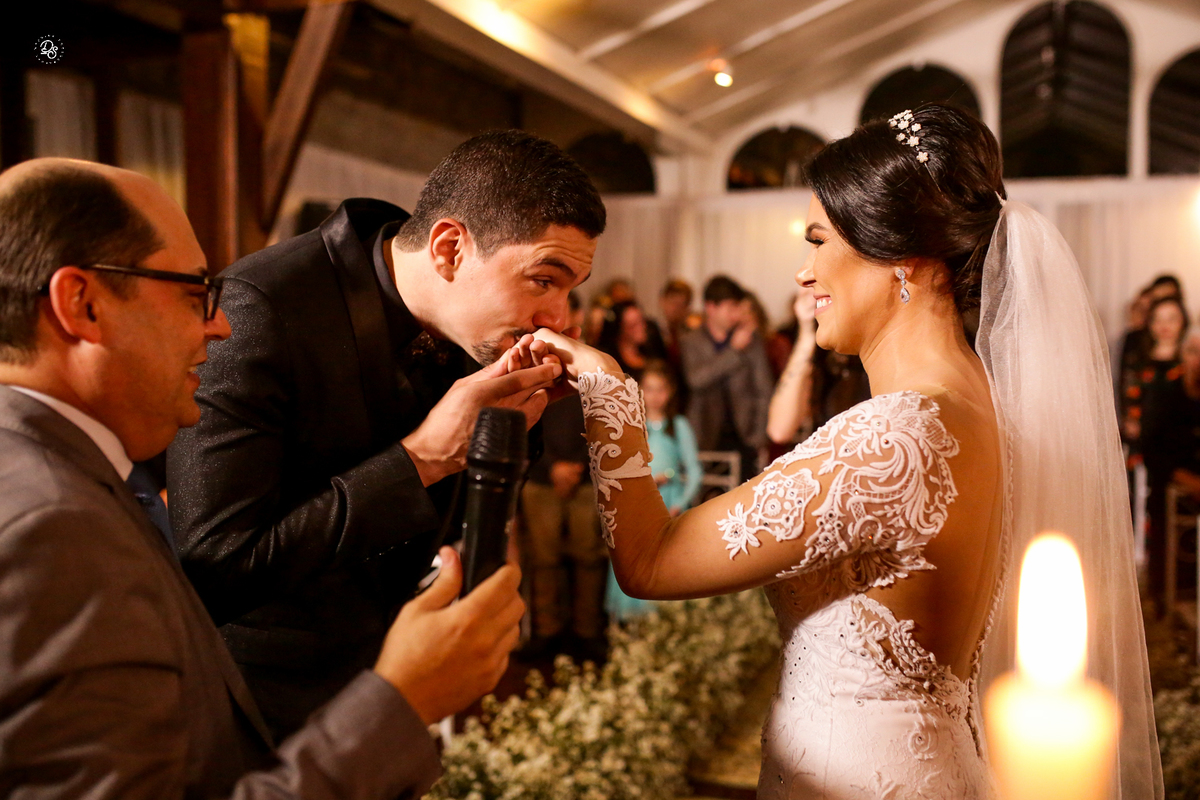 Noivo beijando a mão da noivo após colocar a aliança no seu dedo.