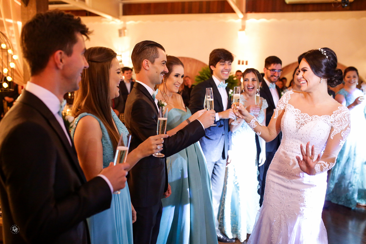 Noiva brindando com os padrinhos ao entrar no salão da recepção.