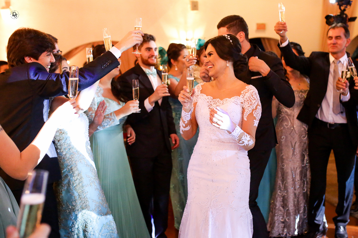Noiva brindando com os padrinhos ao entrar no salão da recepção.
