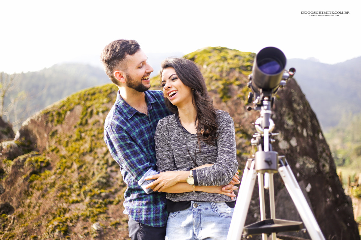 Casal se divertindo ao lado de um telescópio.