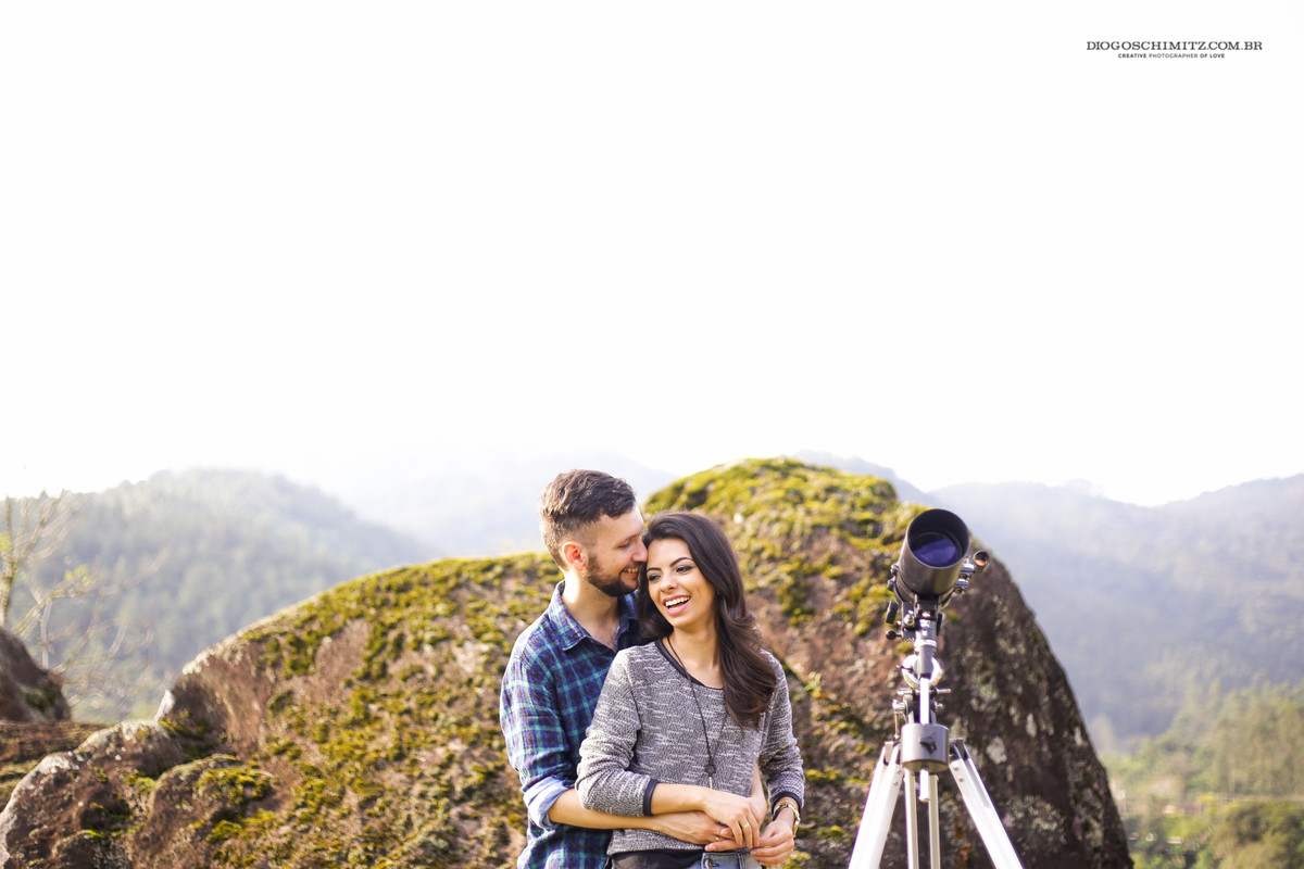 Casal se abraçando ao lado de um telescópio.