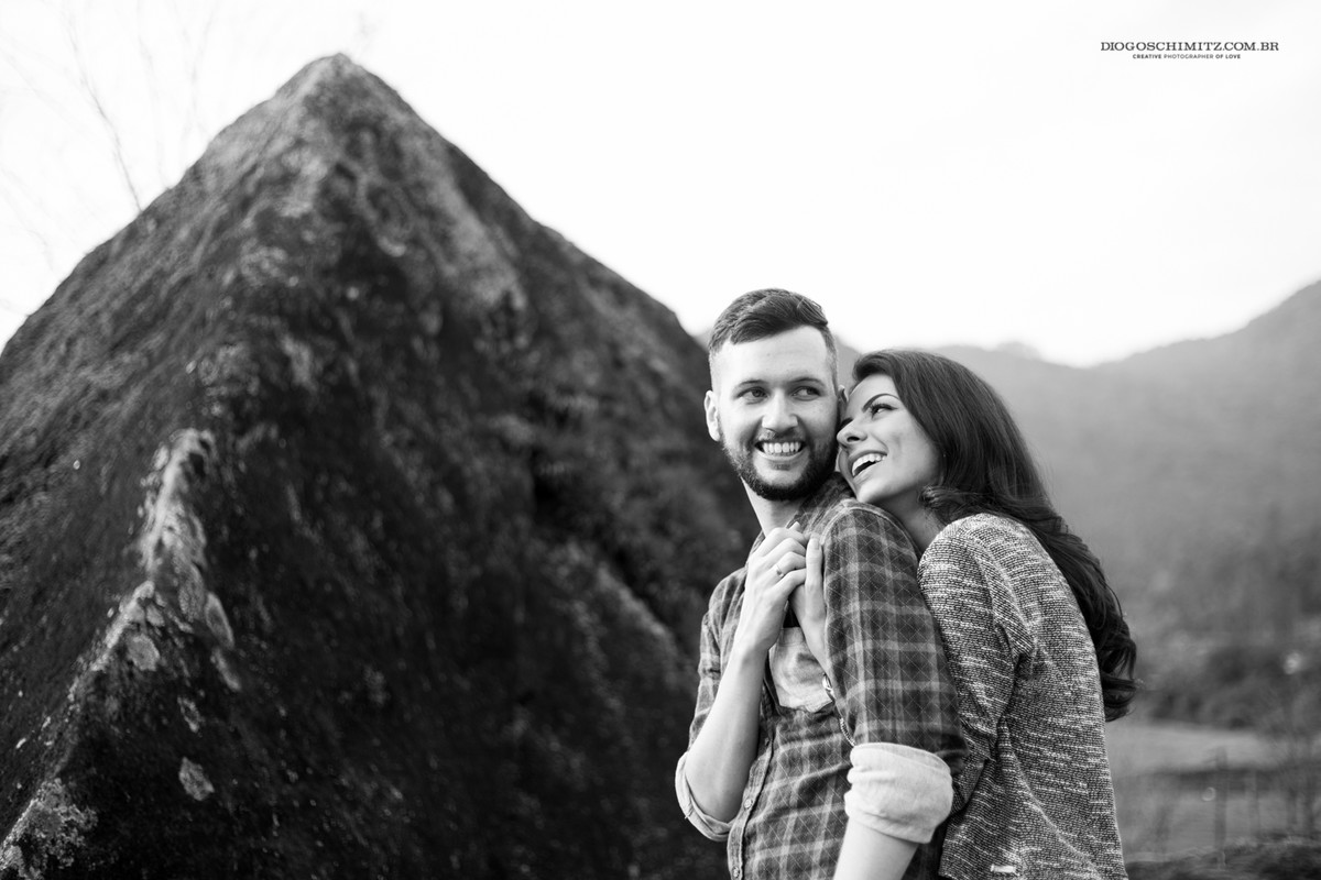 Mulher abraçando o homem pelas costas enquanto os dois sorriem.