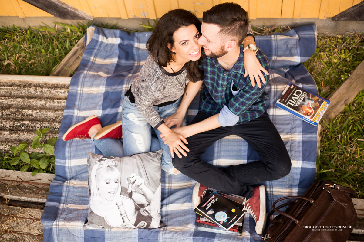 Casal sentado se abraçando e sorrindo, a mulher olhando para cima, enquanto o homem olha para ela.