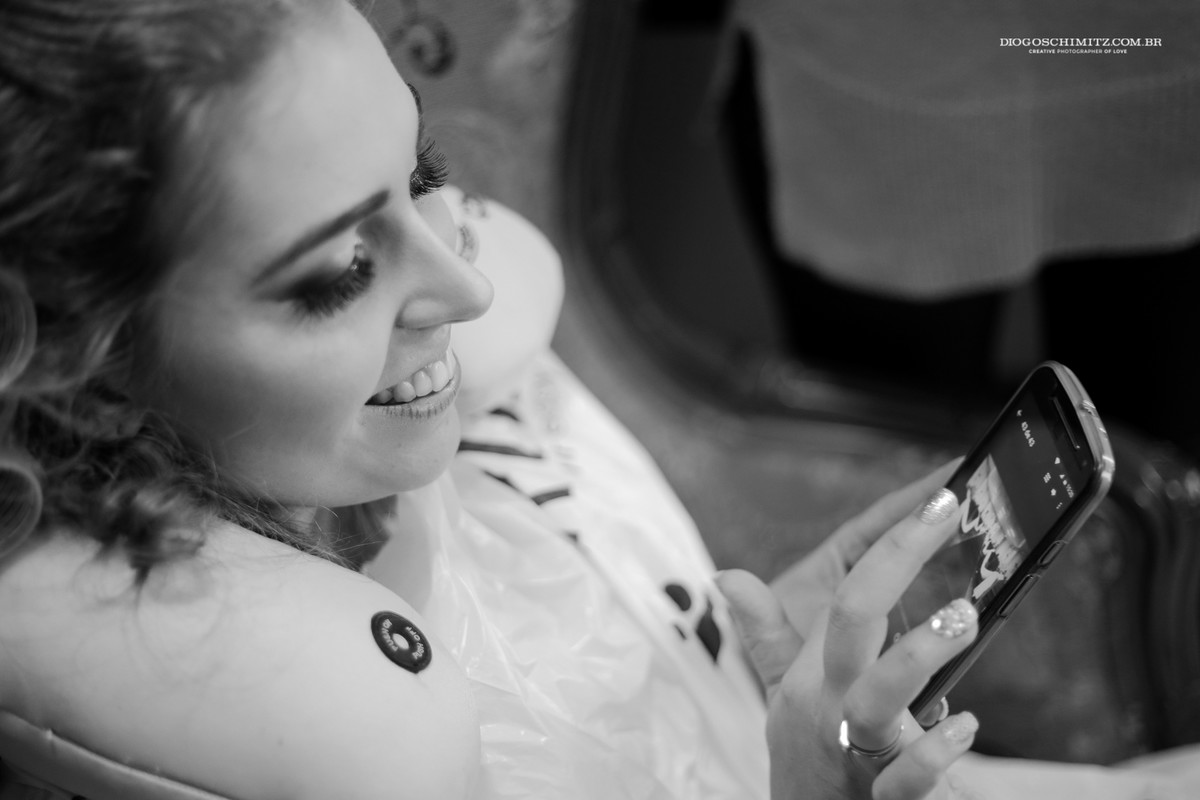 Noiva sorrindo ao olhar o celular.