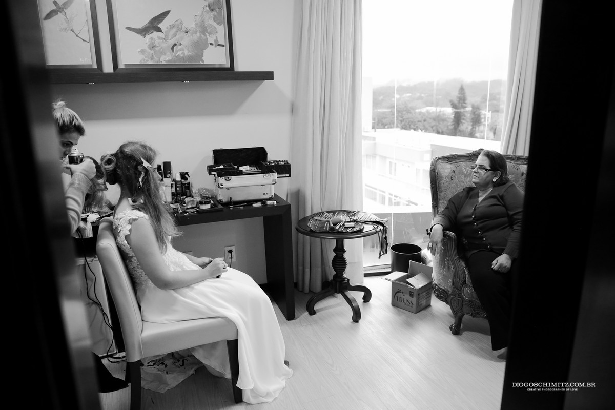 Noiva sentada em frente a sua mãe enquanto seu cabelo é arrumado.