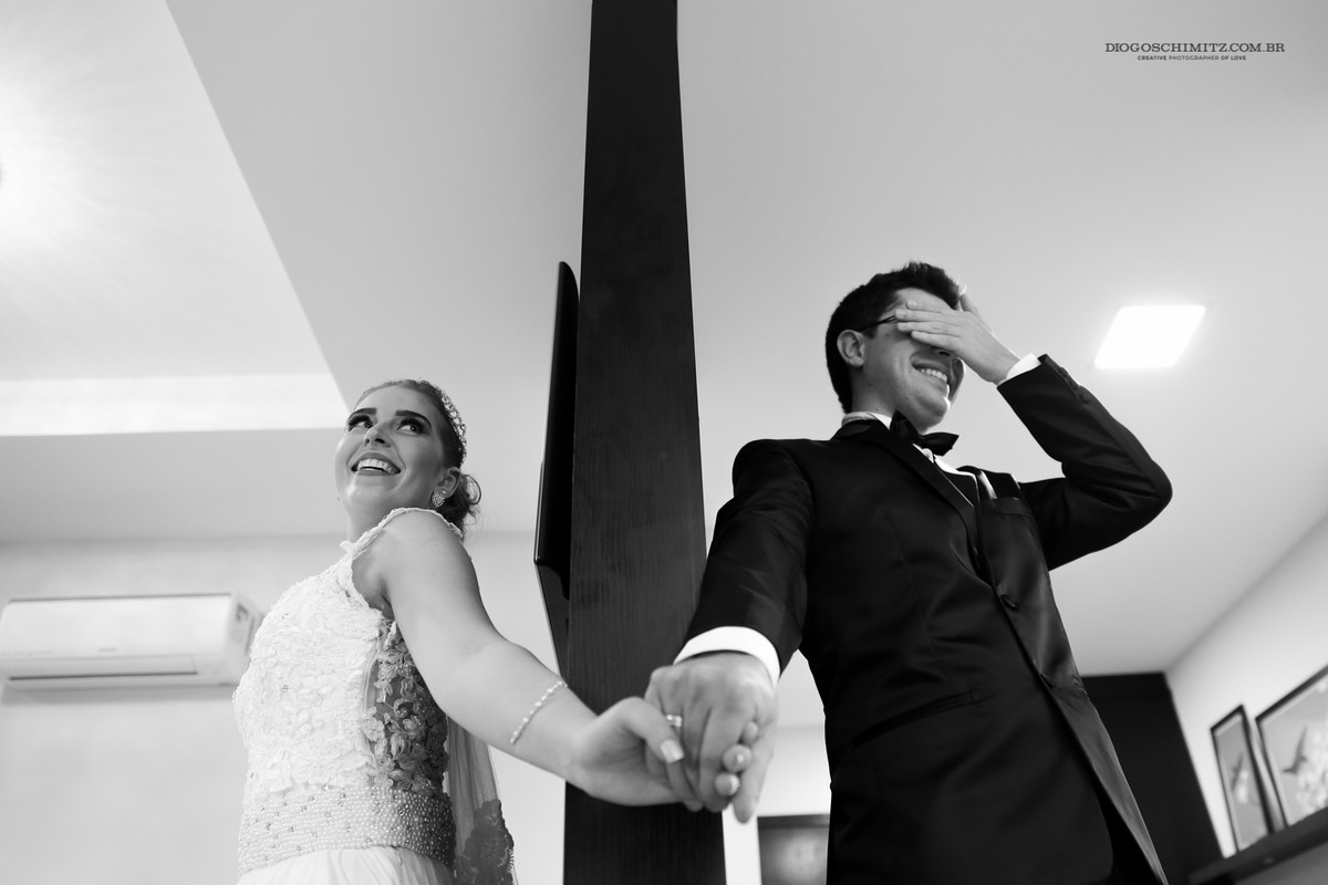 O casal de mãos dadas, escondidos um do outro por uma coluna.