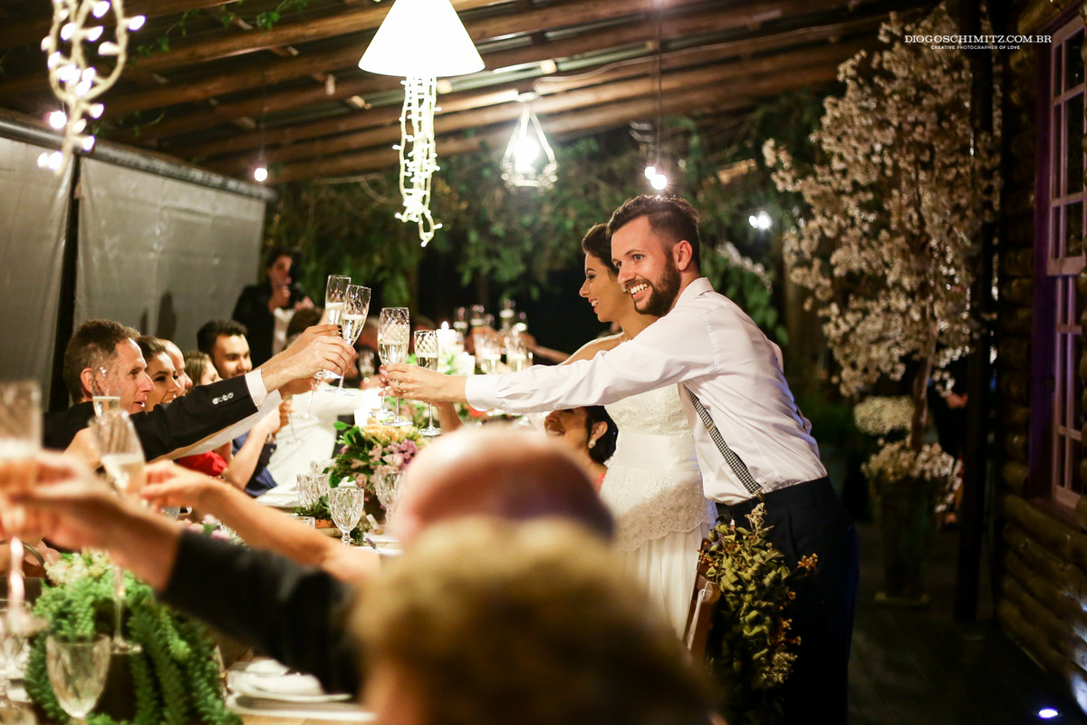 Brinde dos noivos que demonstram alegria no casamento ao ar livre.