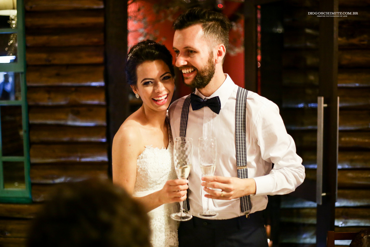 Noivos sorrindo ao brindar o seu casamento.