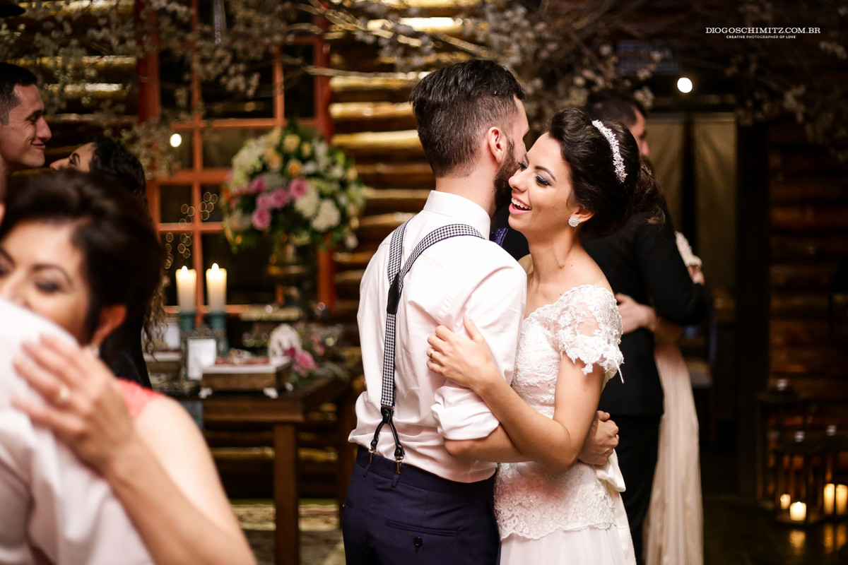 Noiva sorri nos braços do noivo enquanto dançam.
