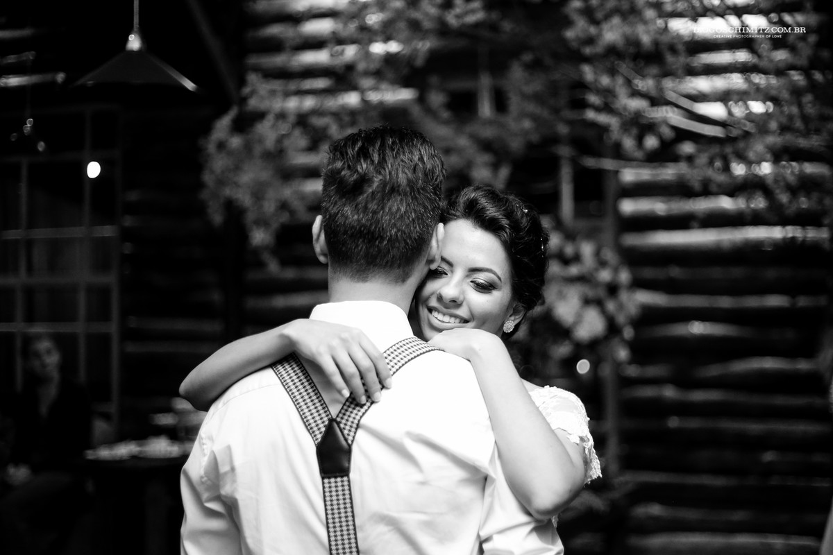 Noiva sorri ao abraçar seu marido.