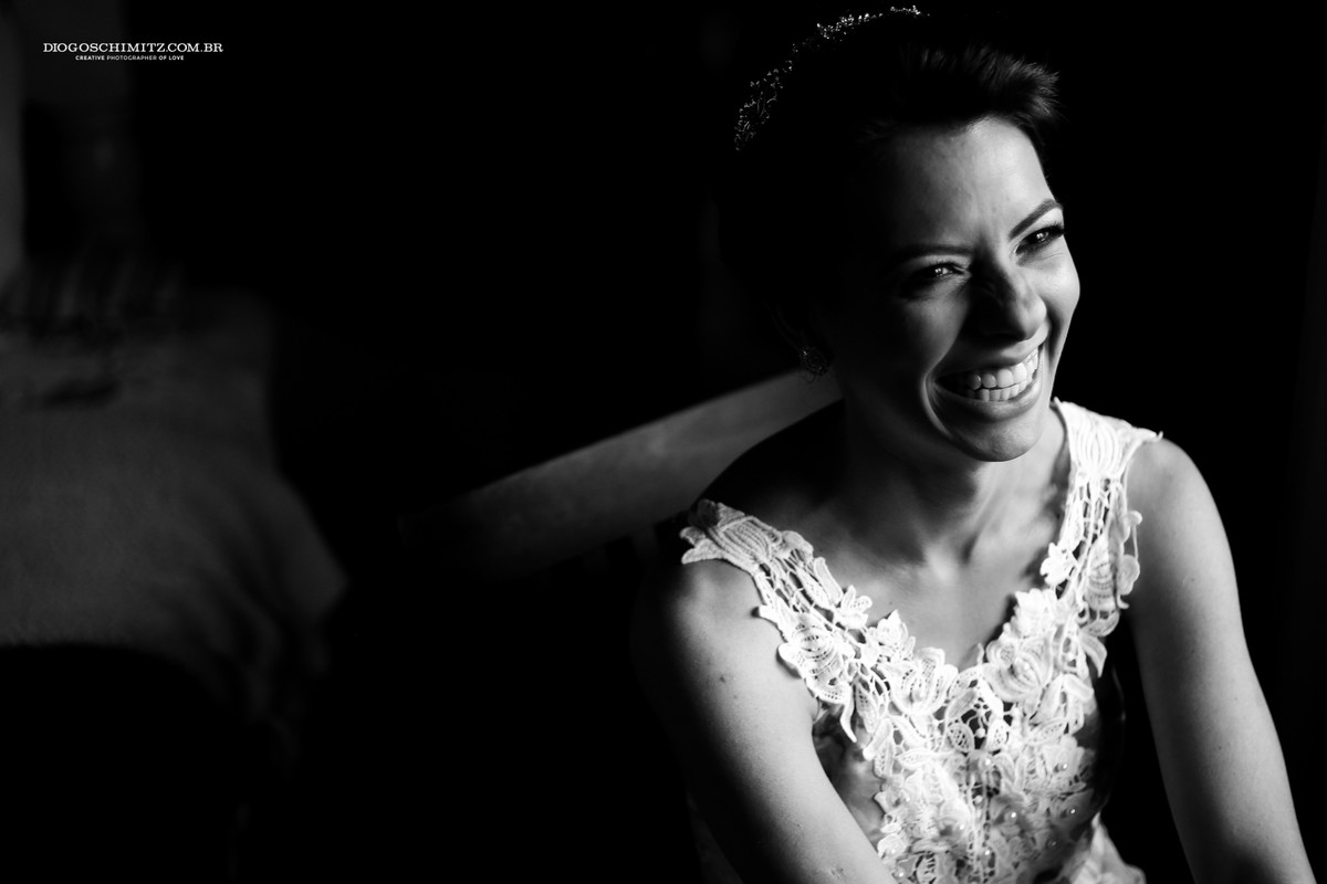 Noiva sorrindo ao ser preparada para o seu casamento no campo.