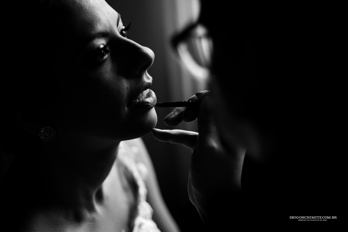 Detalhe da boca da noiva sendo maquiada para o seu casamento no campo.