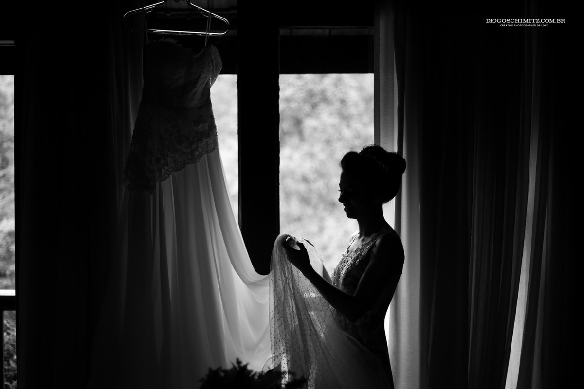 Noiva pegando e sentindo o seu vestido e seu véu antes de se finalizar para o seu casamento no campo.