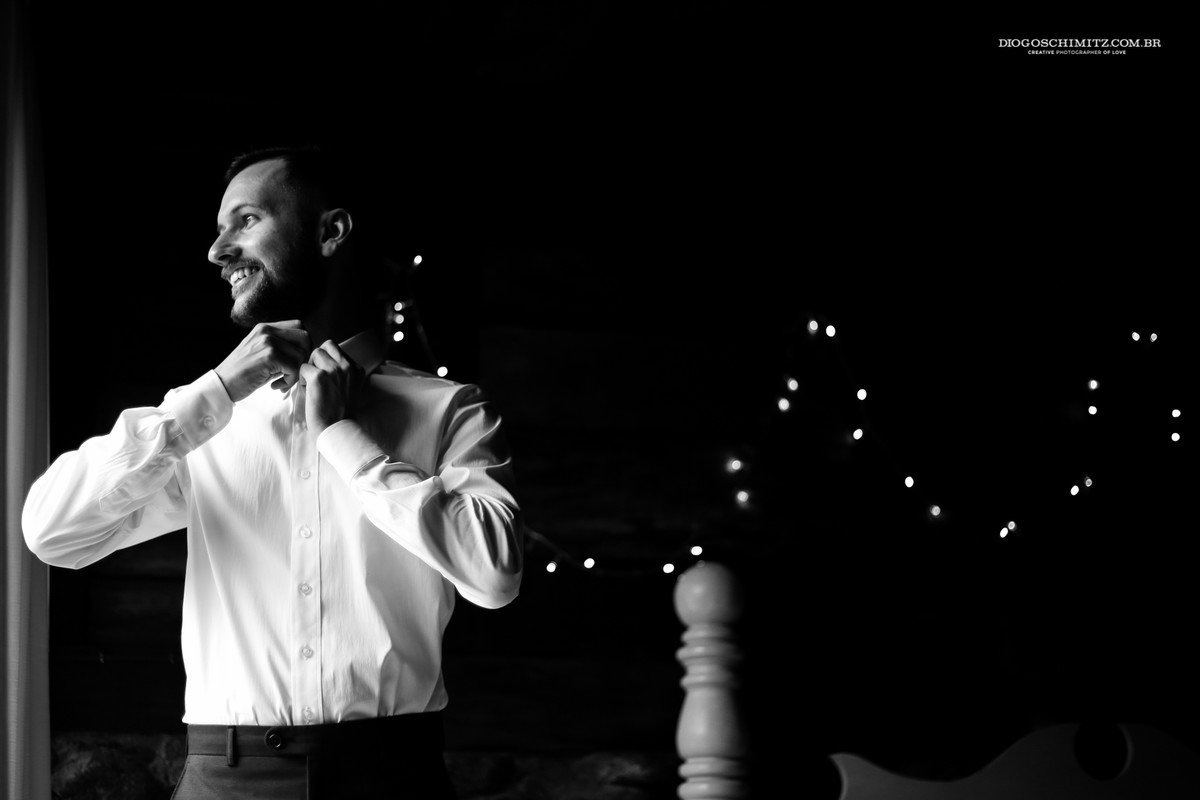 Detalhe de noivo colocando a camisa para o seu casamento no campo.