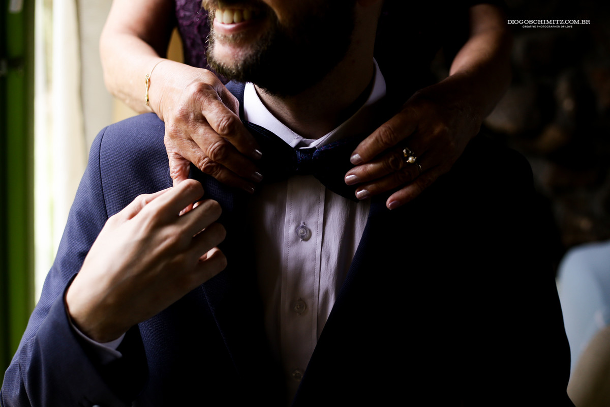 Detalhe da gravata borboleta com as mãos da sua mãe.