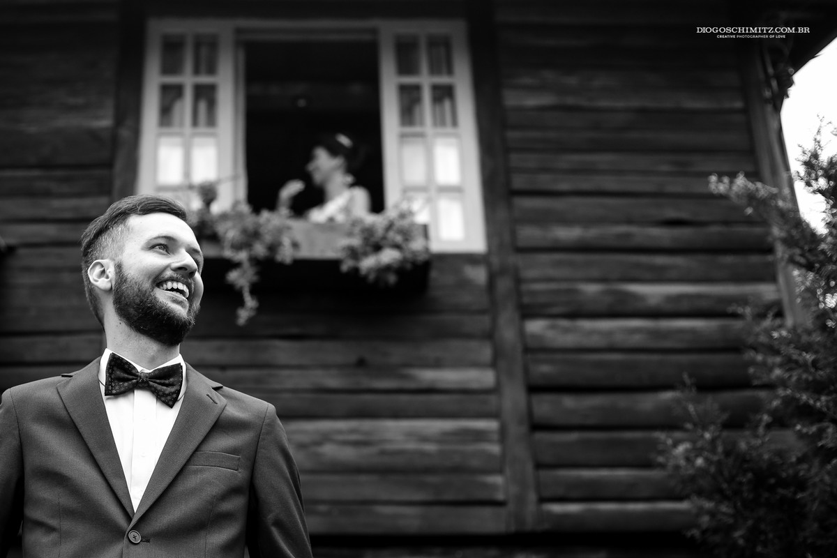 Noivo olhando para frente e noiva ao fundo vendo seu futuro marido indo até o local da cerimônia no campo.